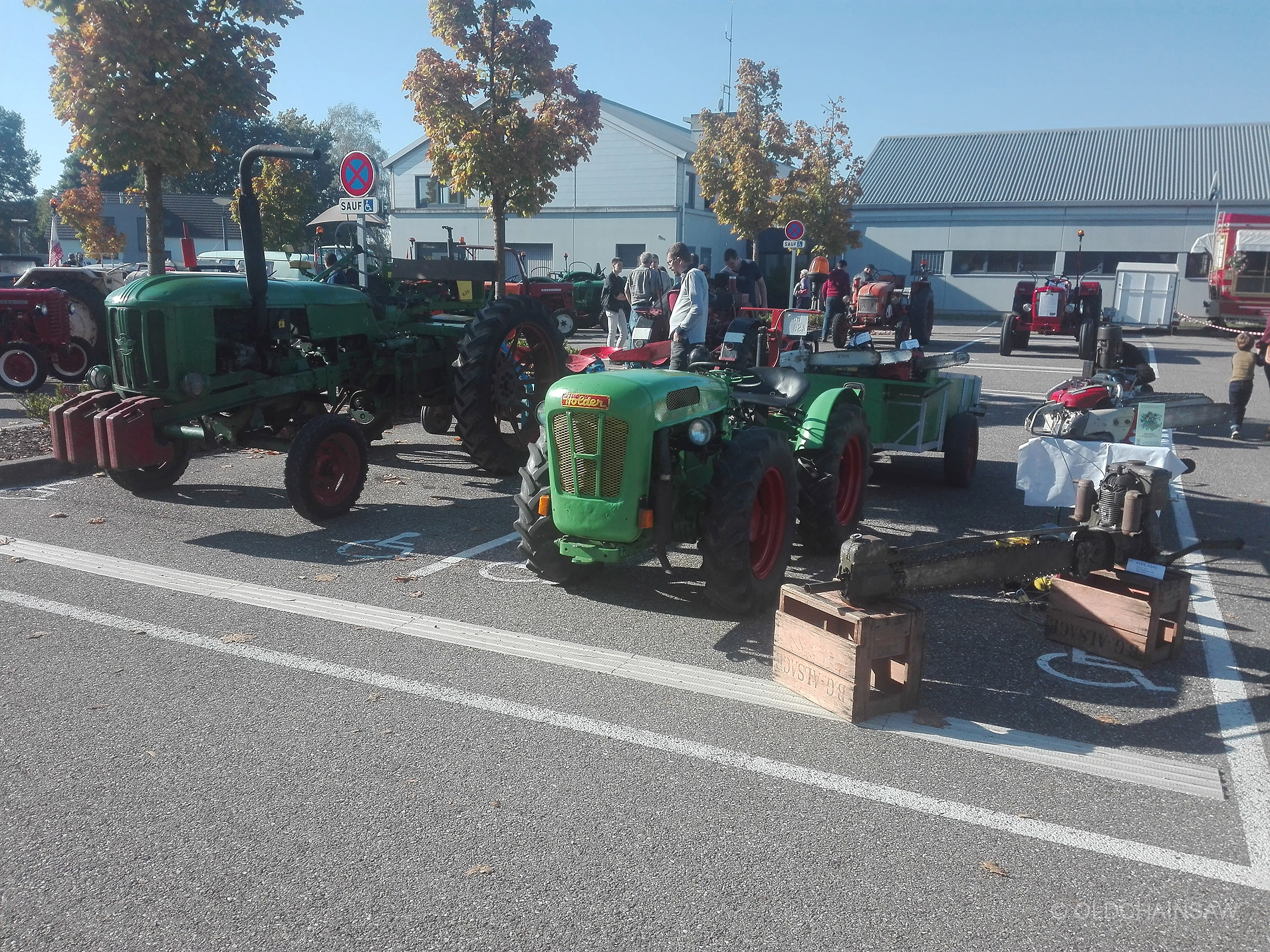 Notre tracteur et sa remorque intégrés à l’exposition OLDCHAINSAW, avec les tronçonneuses présentées à proximité.
