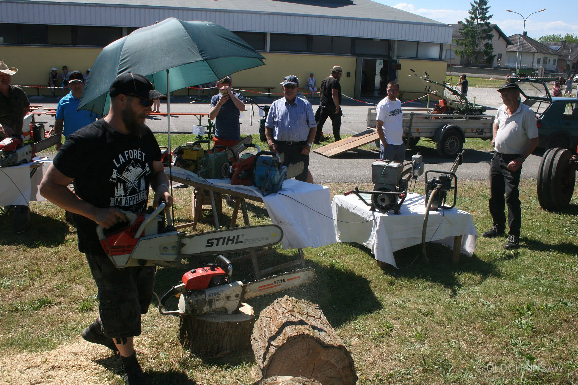 Démonstration avec une tronçonneuse STIHL devant le stand OLDCHAINSAW, sous le regard des visiteurs de la manifestation.